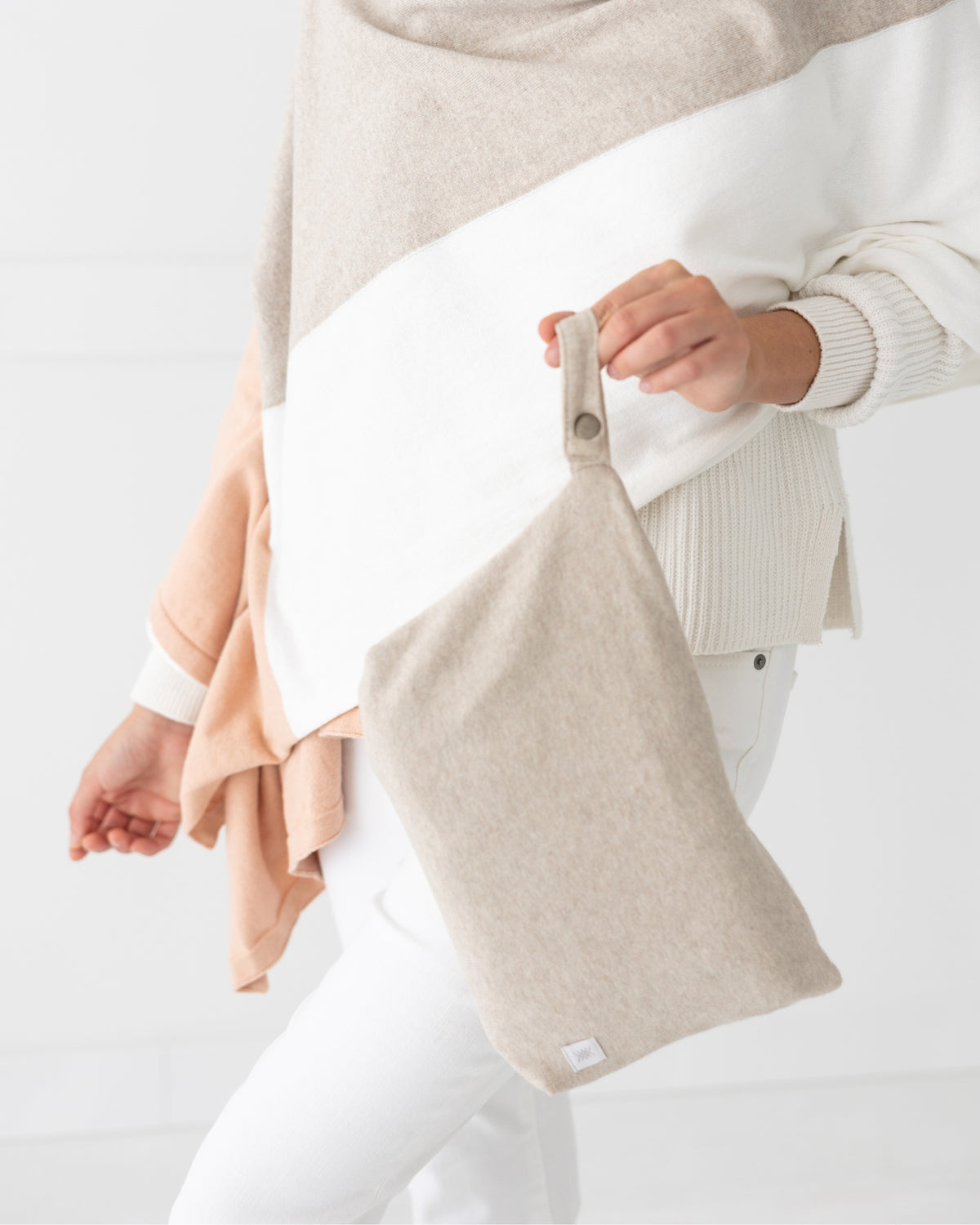Woman carrying Birch Carry Pouch which is a beige zipper pouch that can hold the Dreamsoft Travel Scarf 