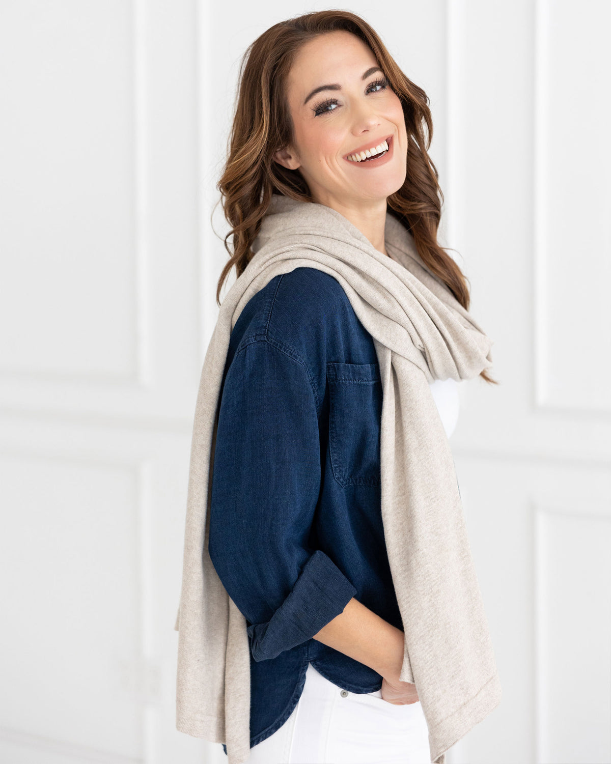 Woman wearing the Dreamsoft Travel Scarf in Birch Scarf which is a cream scarf, while smiling