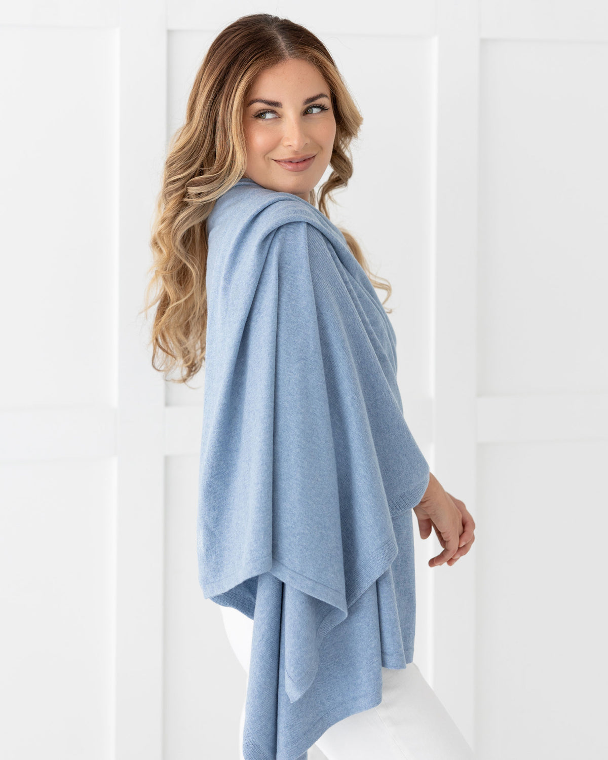 Woman wearing the Cashmere Cotton Luxe Travel Scarf in Horizon Blue which is a light blue scarf, worn as a wrap
