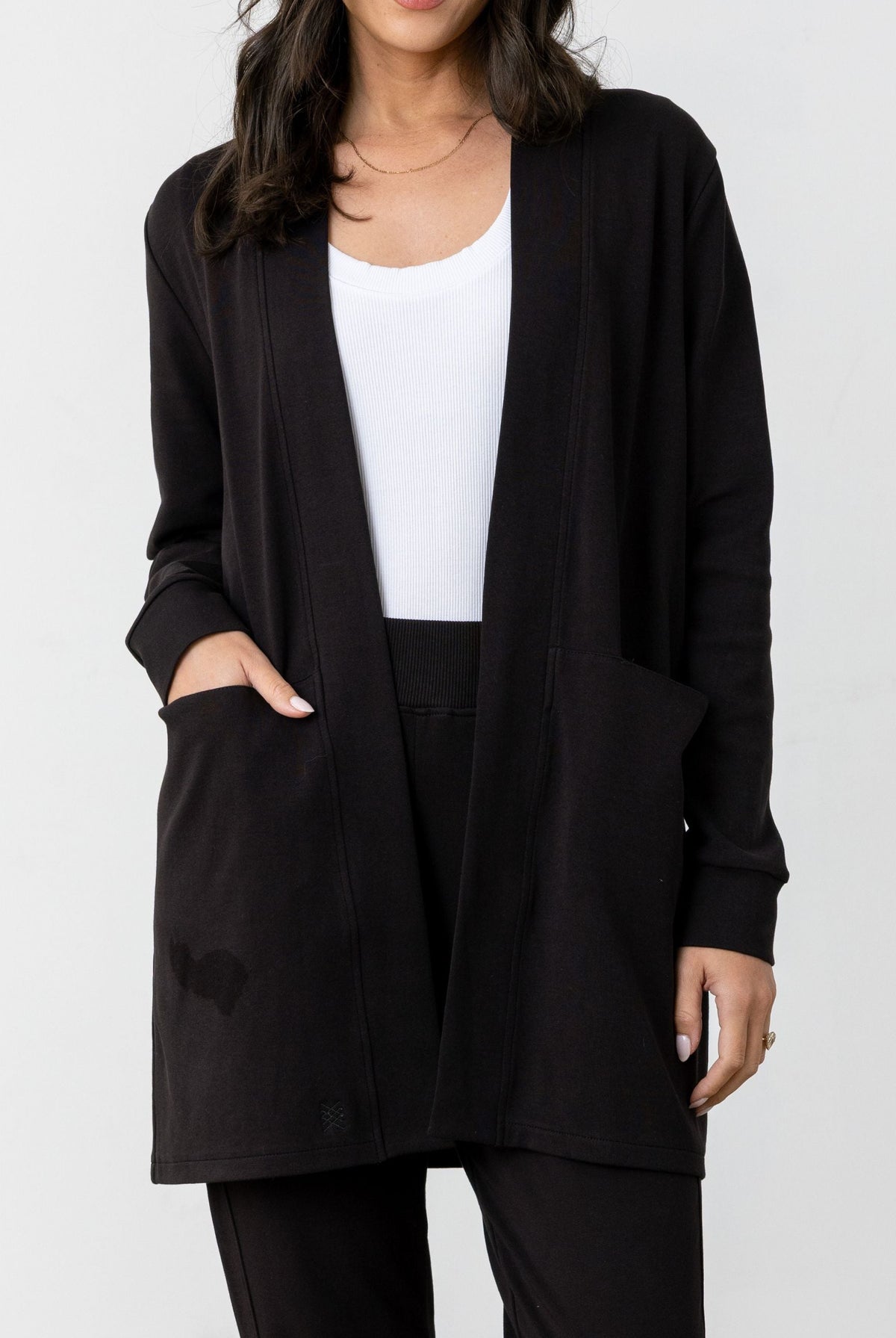 Woman wearing a black cardigan over a white top on a white background