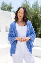Woman shown wearing a blue scarf draped over her shoulders