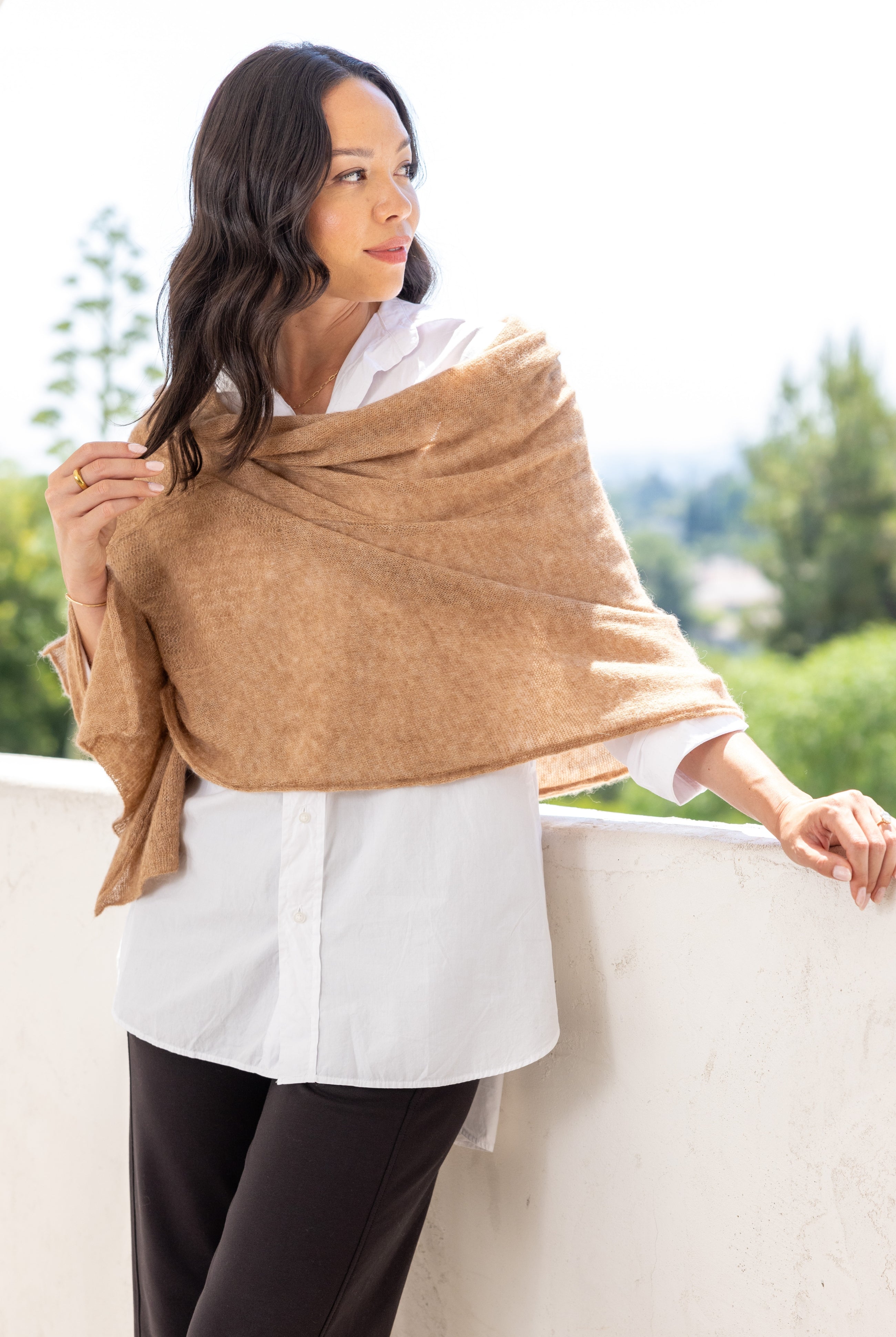 Woman shown wearing a beige scarf draped over her shoulders