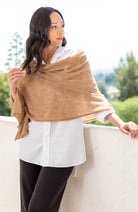Woman shown wearing a beige scarf draped over her shoulders