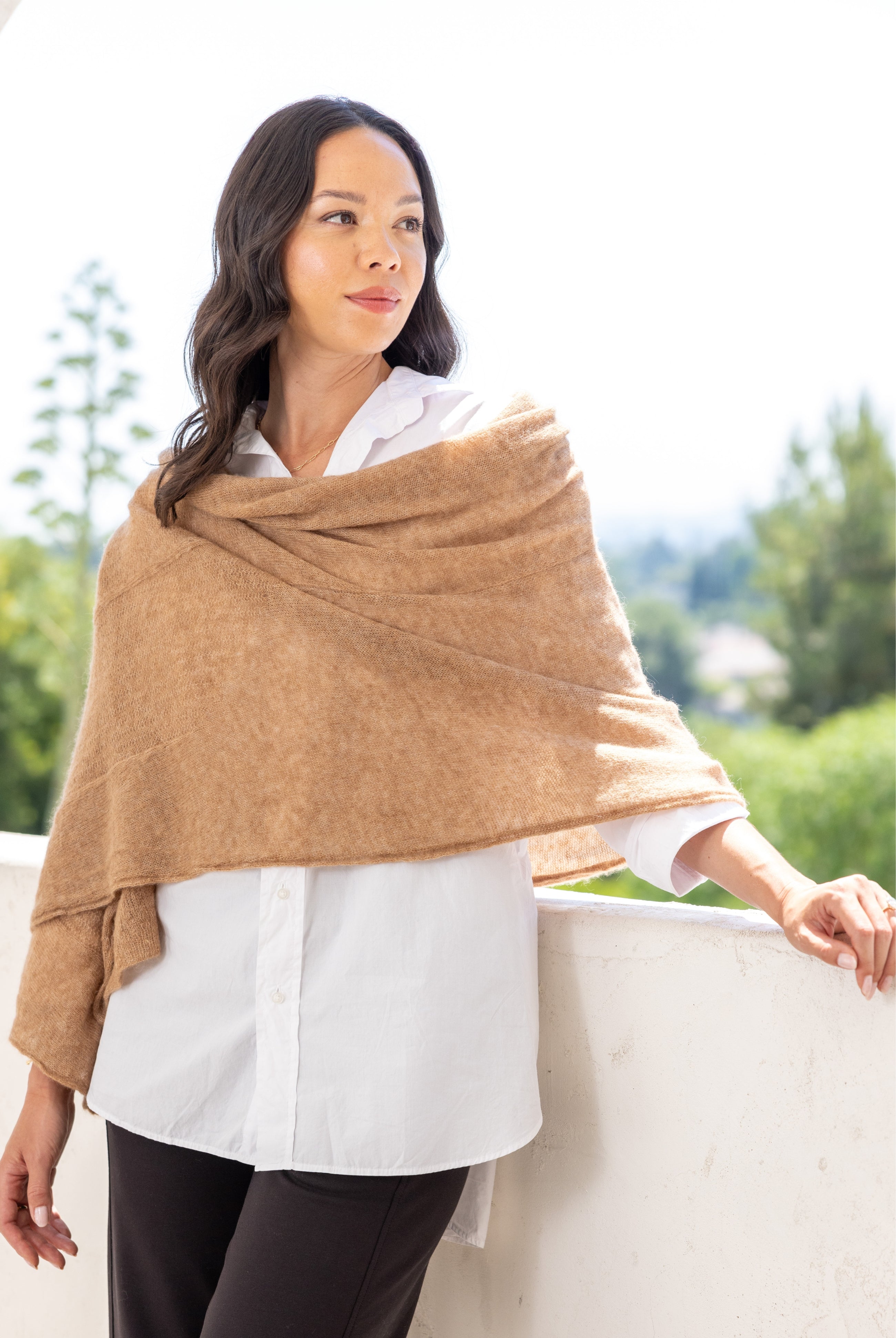 Woman shown wearing a beige scarf draped over her shoulders