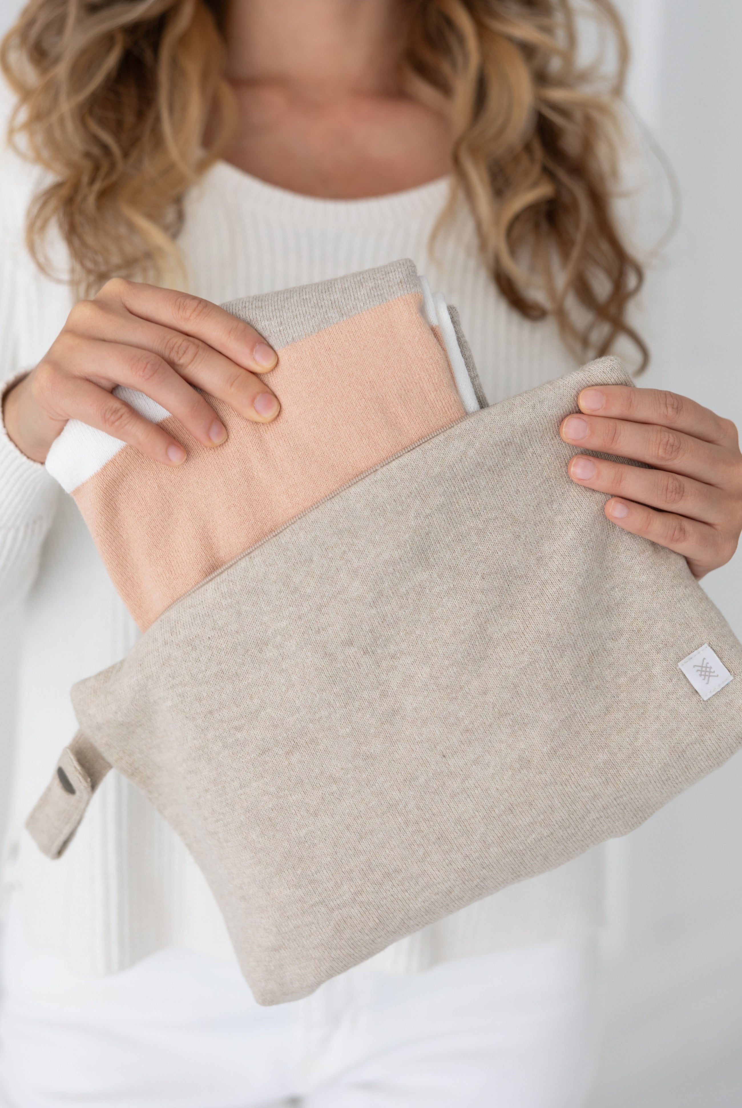 Woman shown pulling scarf out of the beige carry pouch