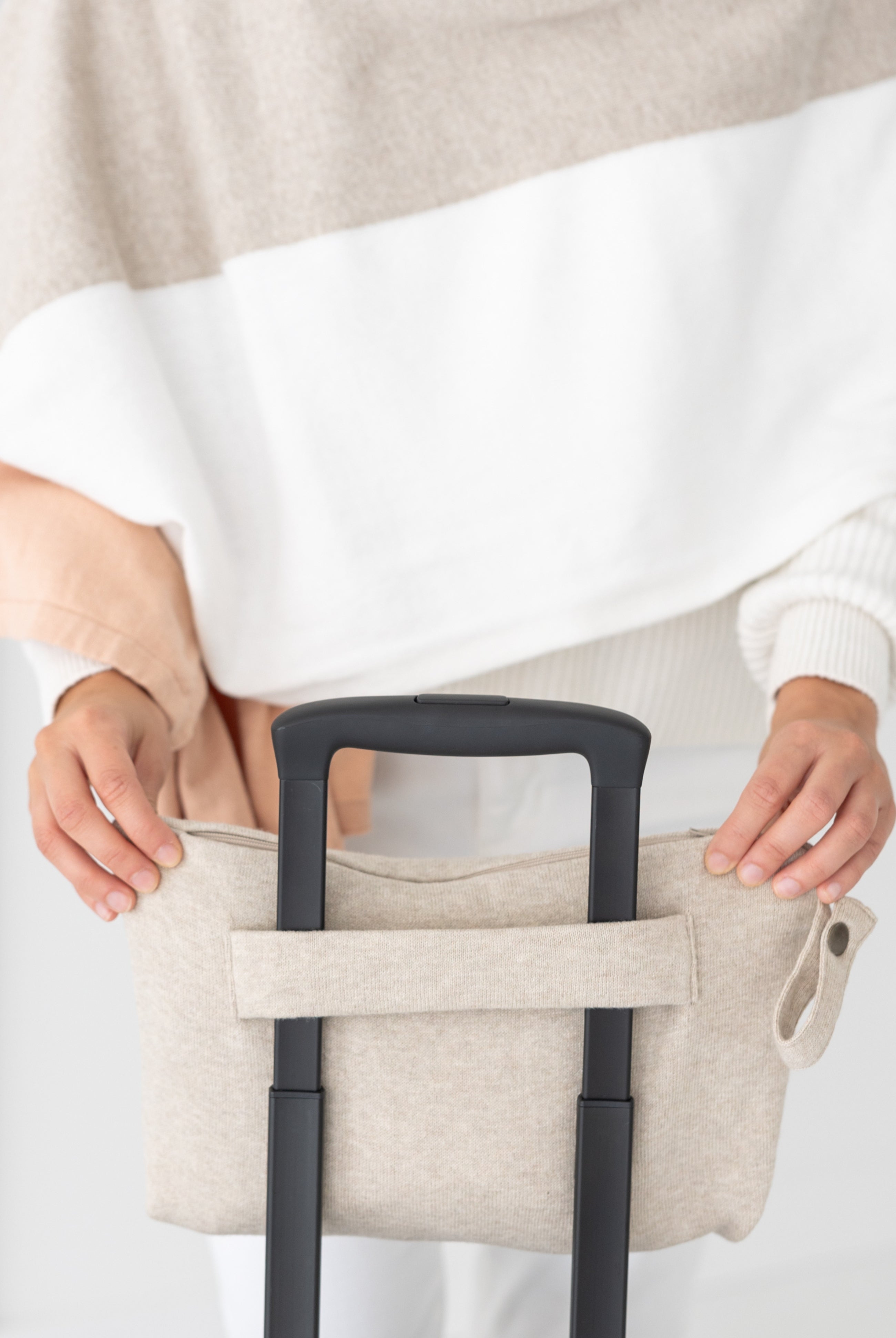 Woman shown putting beige carry pouch on luggage handle