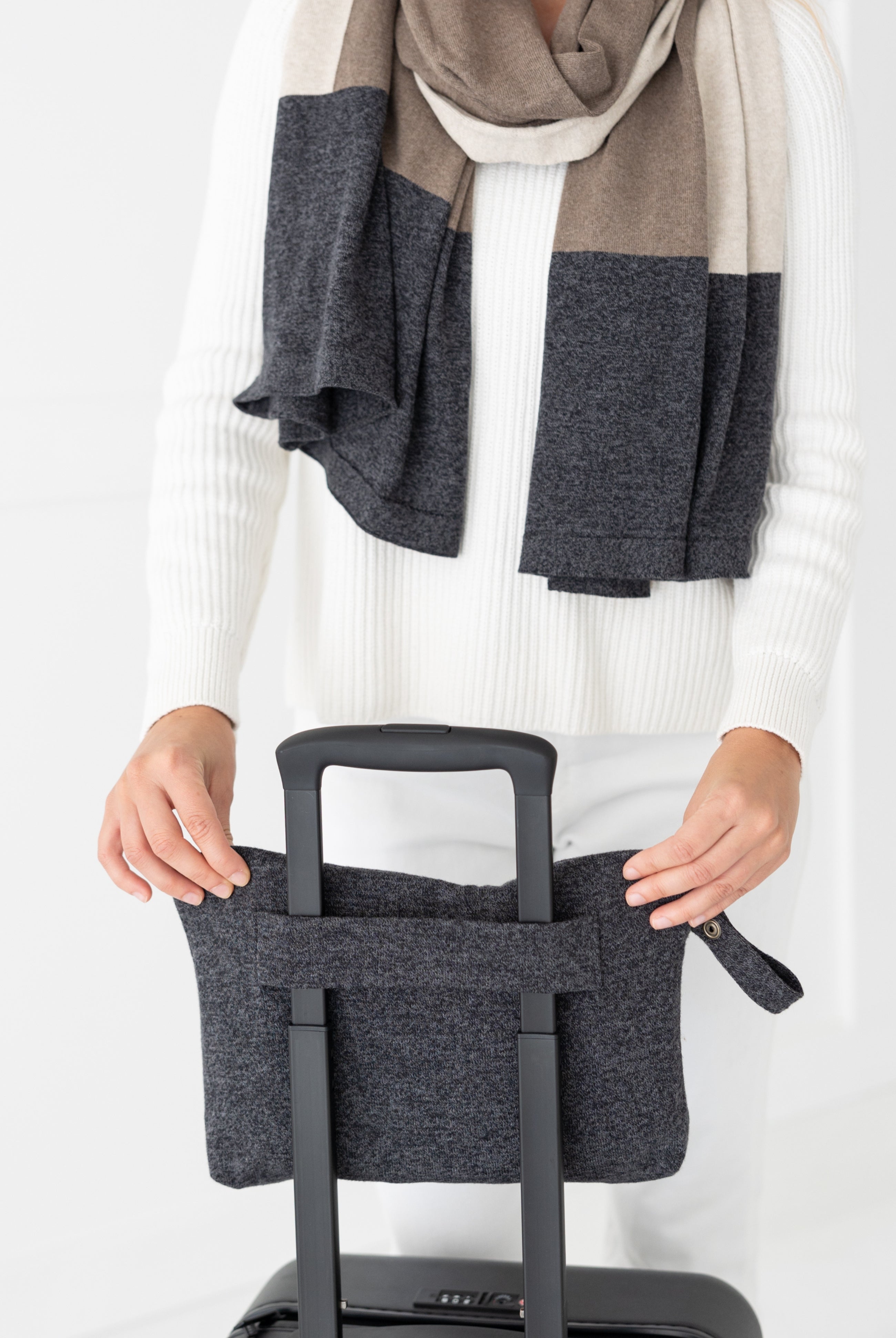 Woman shown puttingGray carry pouch on luggage handle