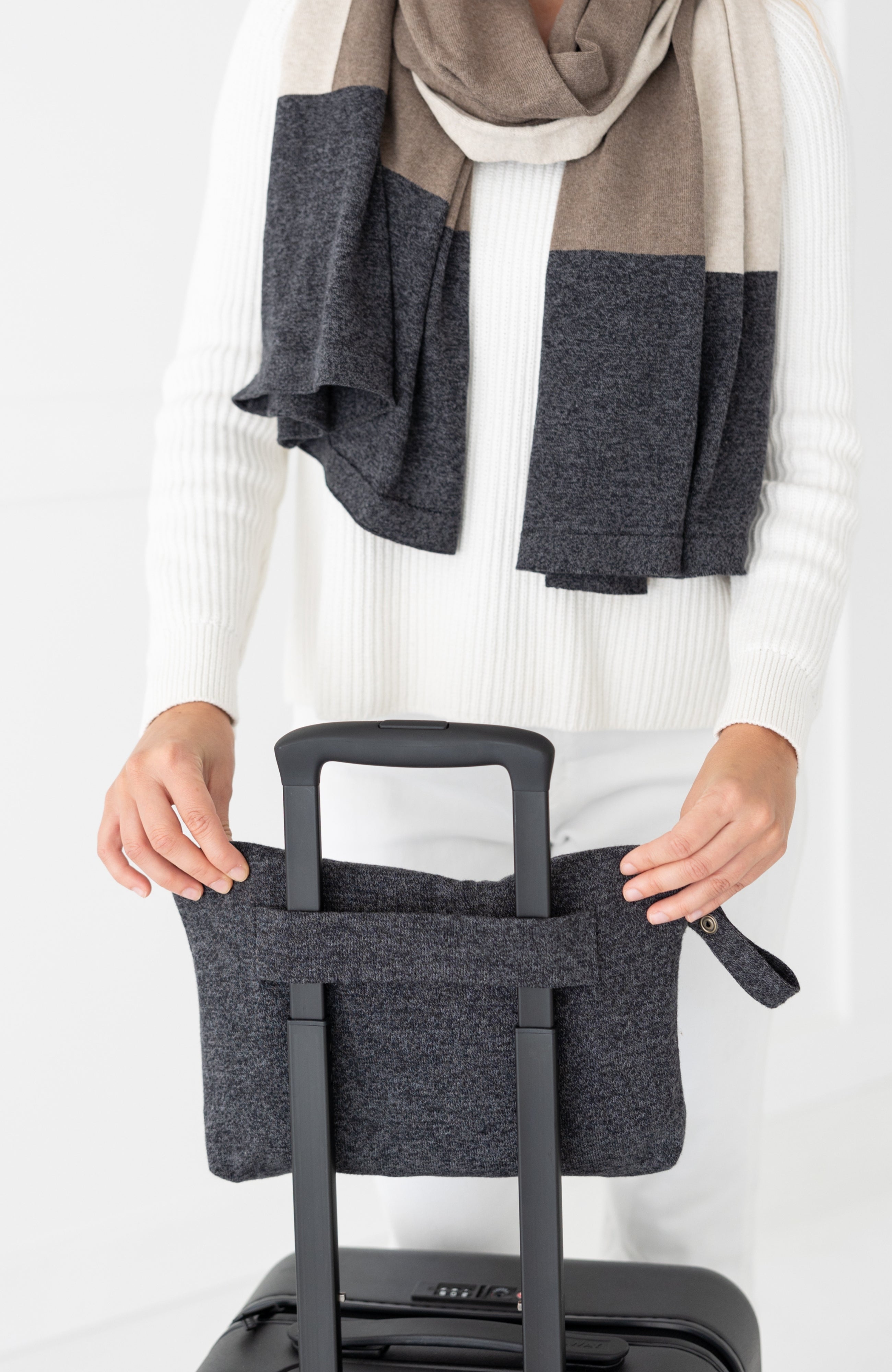 Woman shown puttingGray carry pouch on luggage handle