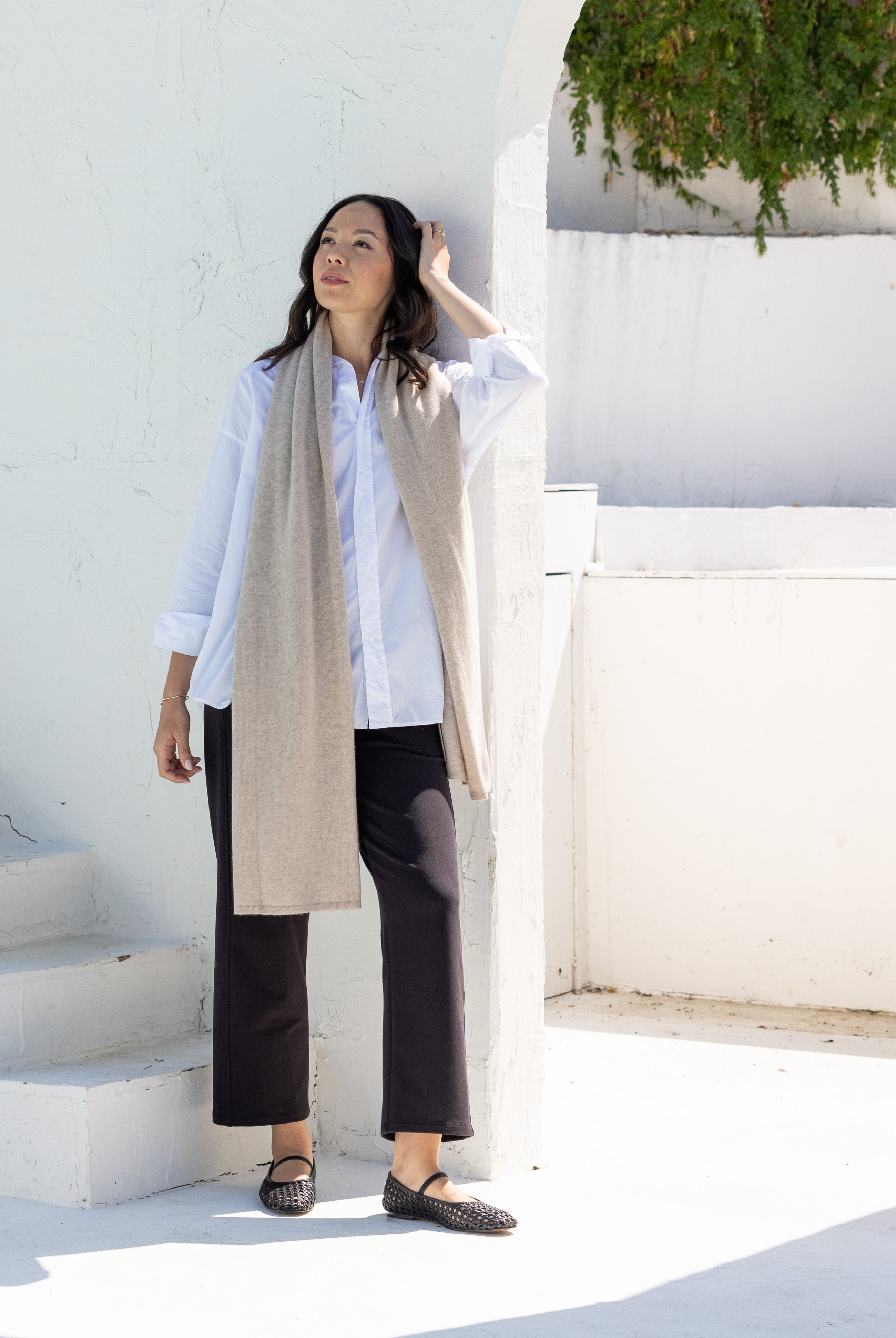 Woman shown wearing a beige scarf draped around her neck