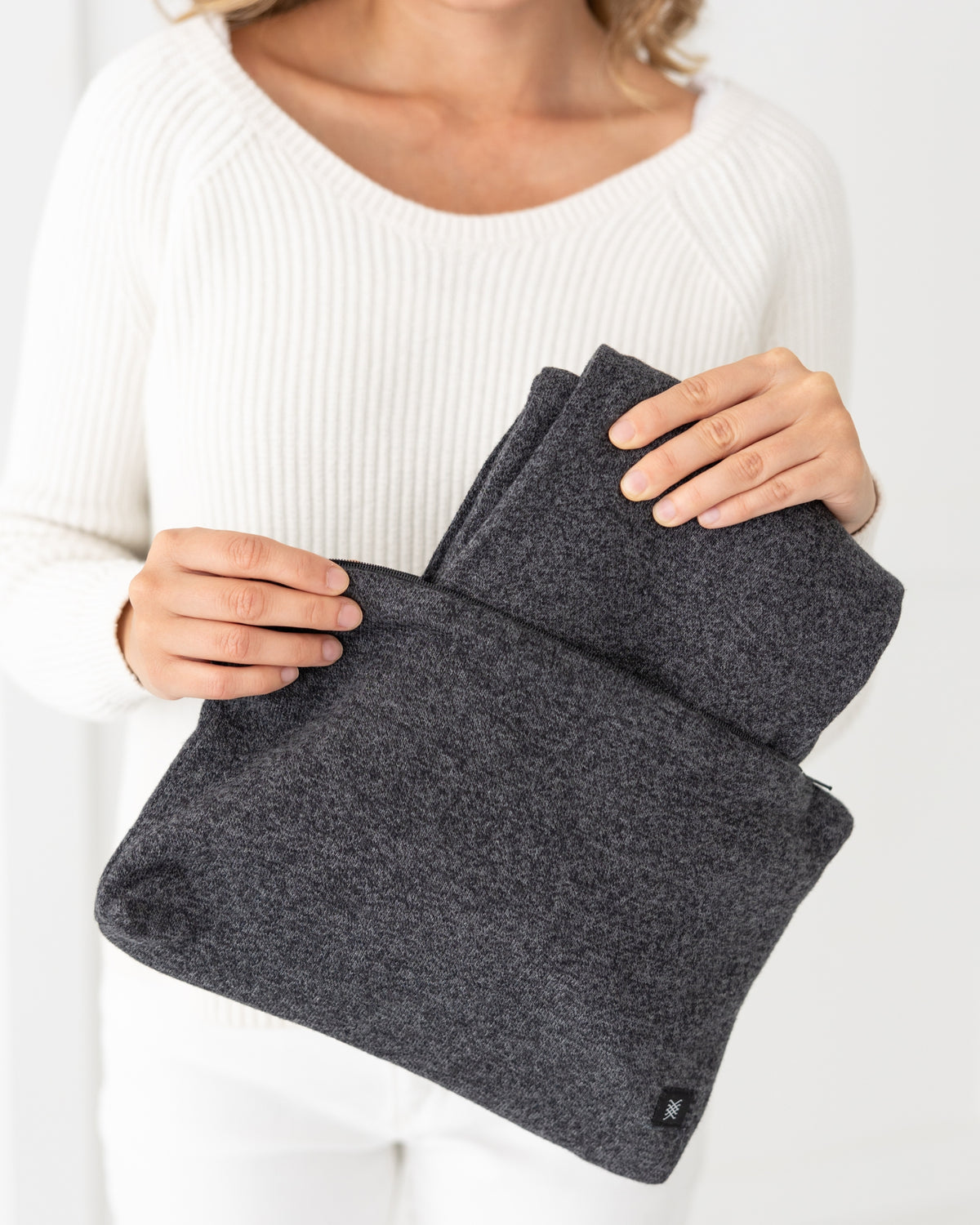 Woman holding Graphite Carry Pouch, which is a gray zipper pouch that can hold the Dreamsoft Travel Scarf. Graphite Dreamsoft Travel Scarf being shown taken out of the carry pouch.