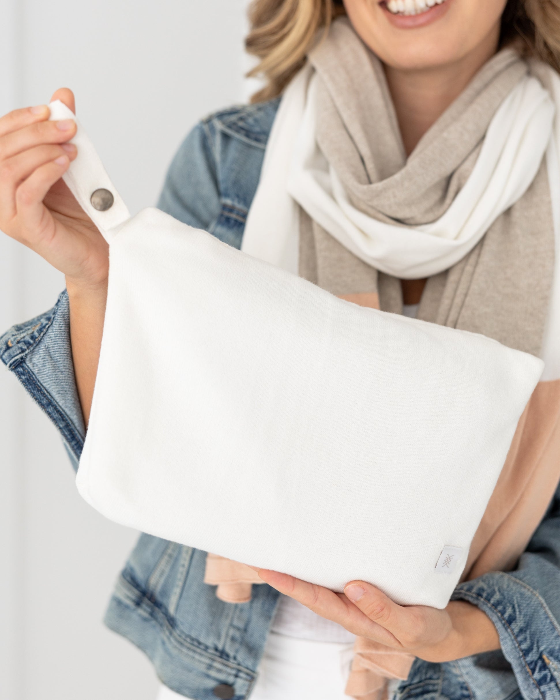 Woman holding Ivory Carry Pouch, which is an off white zipper pouch that can hold the Dreamsoft Travel Scarf