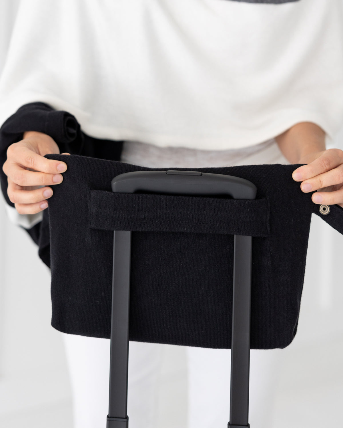 Woman placed Black Carry Pouch that can hold the Dreamsoft Travel Scarf over handle on suitcase