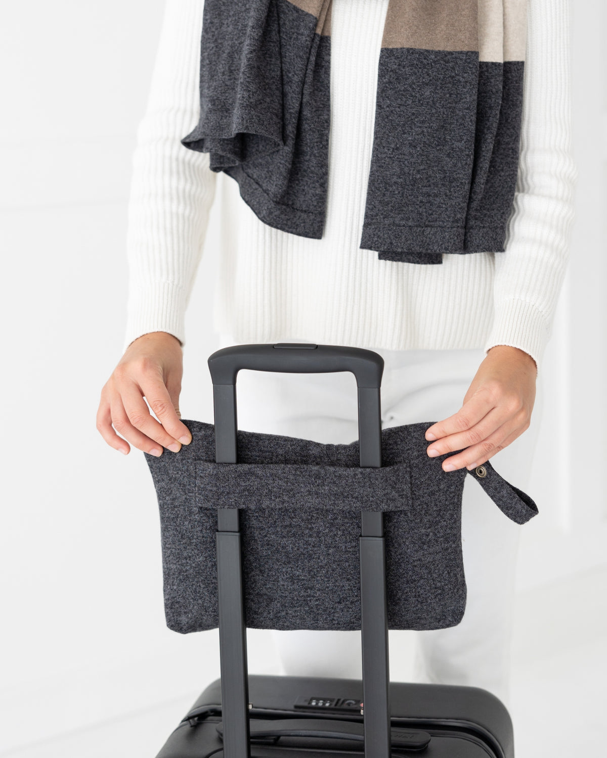 Woman placed Graphite Carry Pouch which is a gray zipper pouch that can hold the Dreamsoft Travel Scarf over handle on suitcase