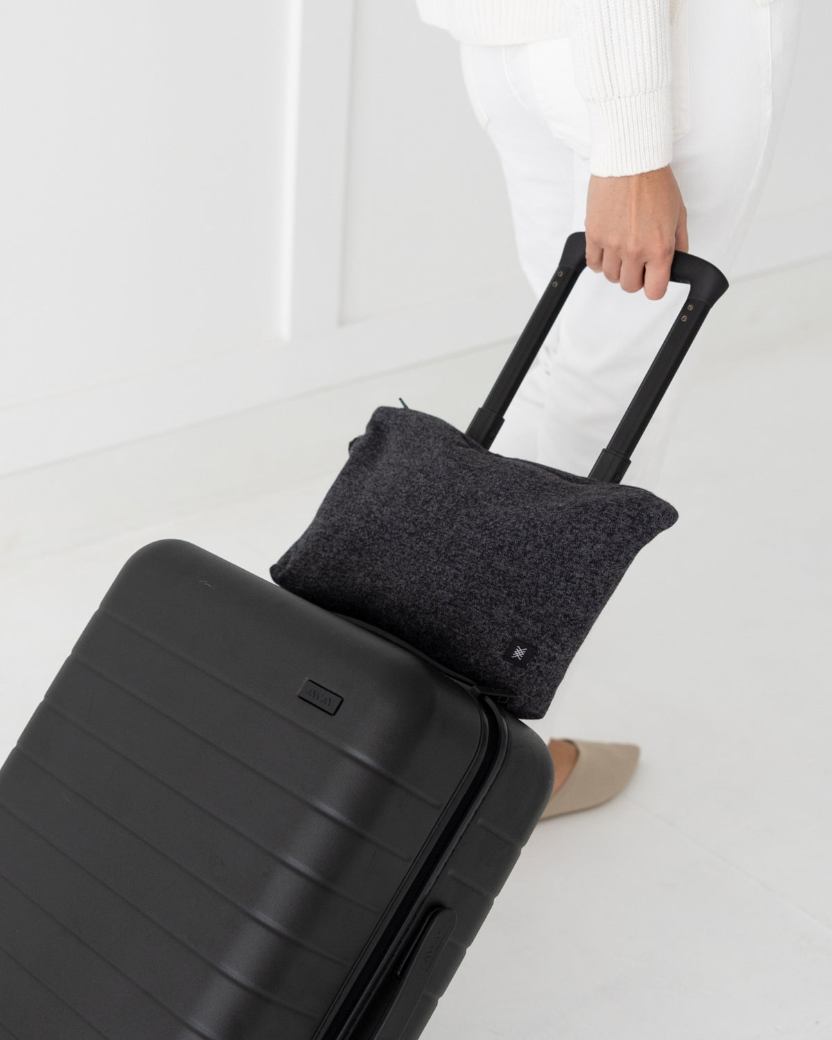 Woman pulling a suitcase with Graphite Carry Pouch, which is a gray carry pouch, attached over the suitcase handle