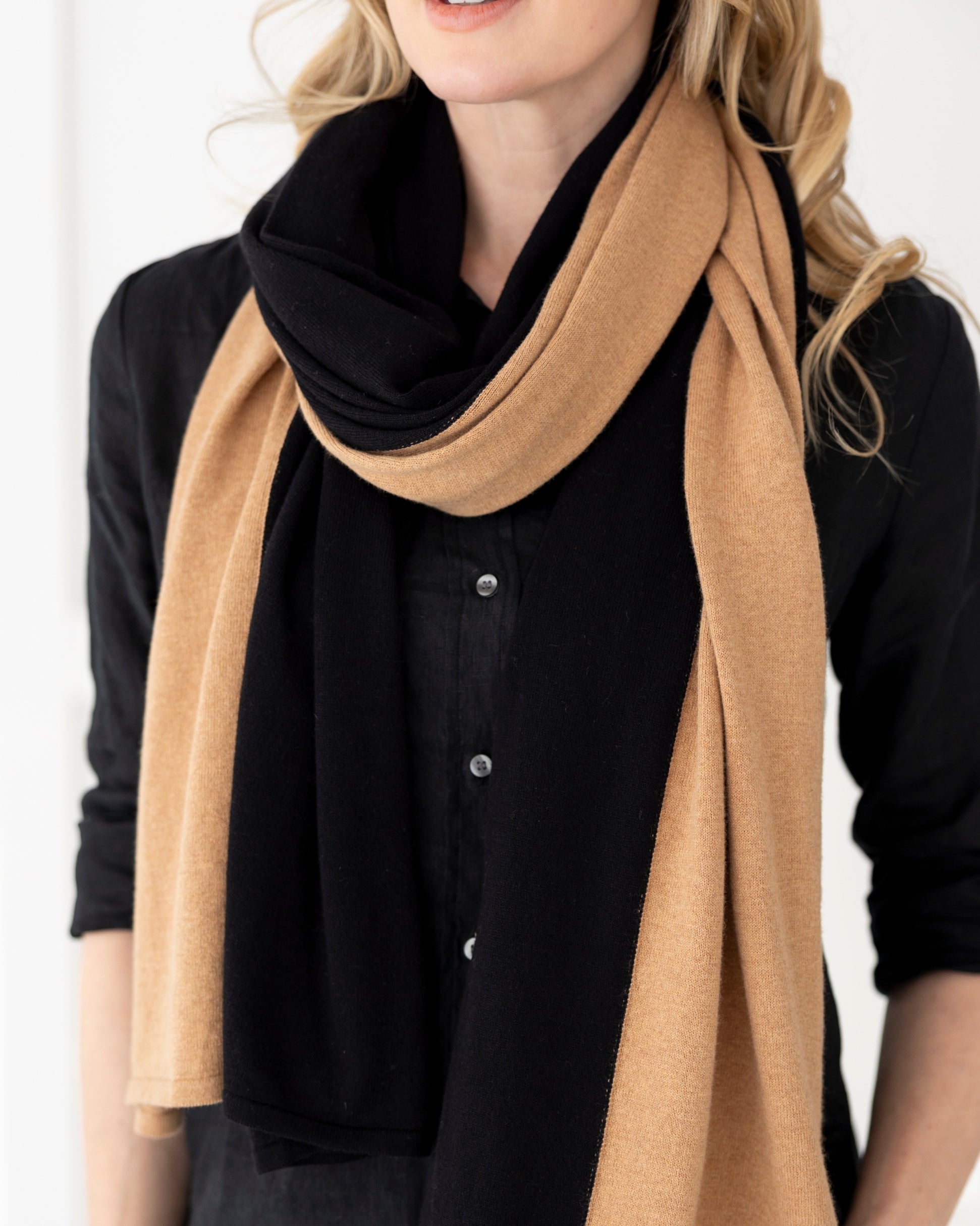 Woman wearing the Cashmere Cotton Luxe Travel Scarf in Black and Camel, which is a beige