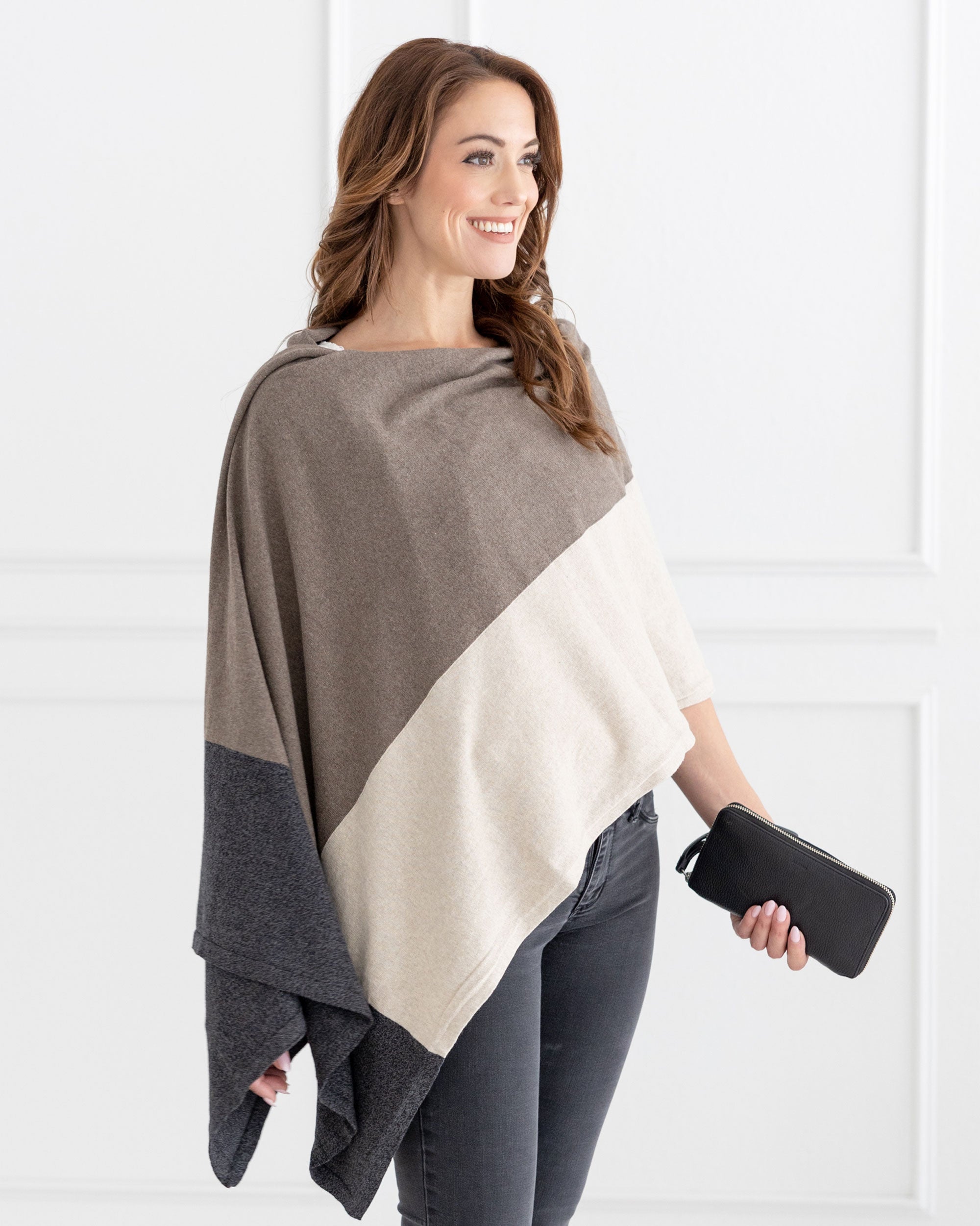 Woman wearing the Dreamsoft Travel Scarf in Brownstone Colorblock which is a brown, tan and gray scarf, worn as a wrap while holding a wallet in her hand