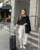 Woman wearing the Dreamsoft Travel Scarf in Black holding suitcase handle