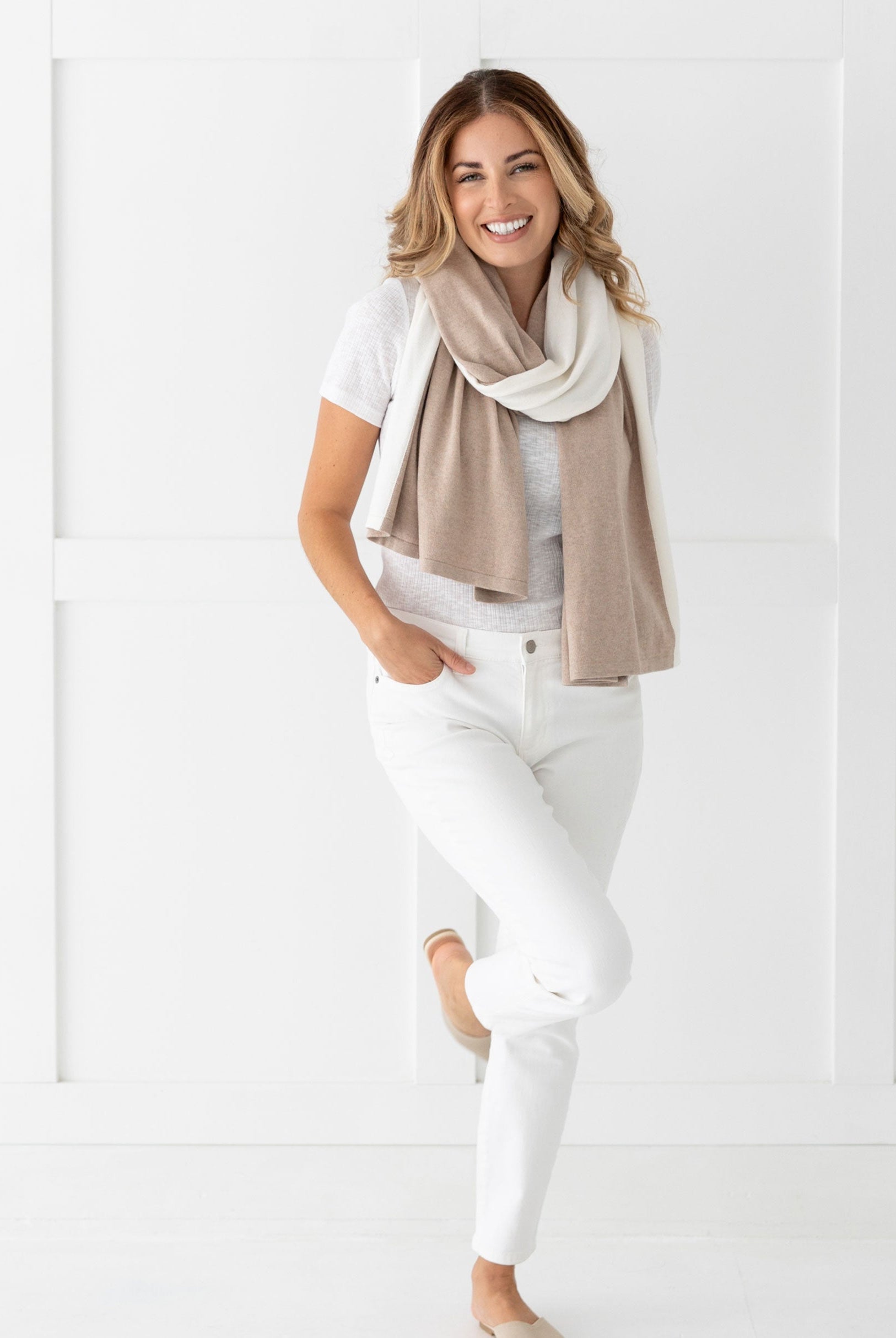 Woman wearing the Cashmere Cotton Luxe Travel Scarf in Sandstone and Ivory Colorblock which is a tan and cream scarf, wearing it as a modern loop