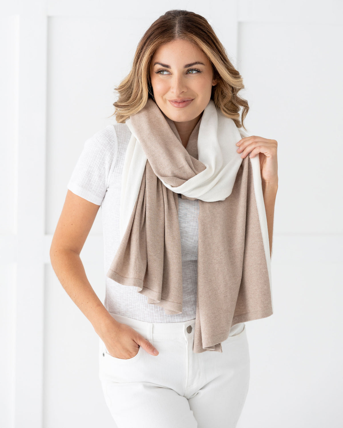 Woman wearing the Cashmere Cotton Luxe Travel Scarf in Sandstone and Ivory Colorblock which is a tan and cream scarf, worn as a modern loop style
