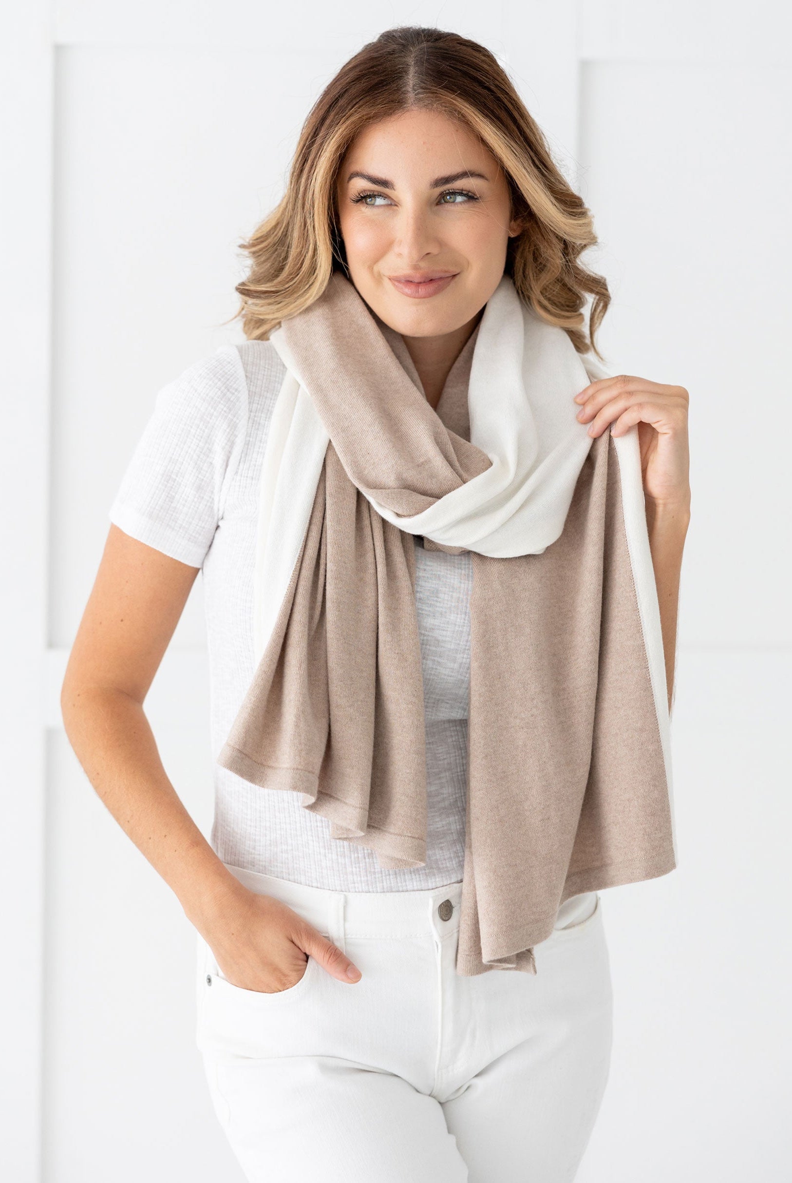 Woman wearing the Cashmere Cotton Luxe Travel Scarf in Sandstone and Ivory Colorblock which is a tan and cream scarf, worn as a modern loop style