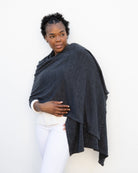 Woman wearing the Dreamsoft Travel Scarf in Graphite which is a gray scarf, worn as the wrap over her shoulder