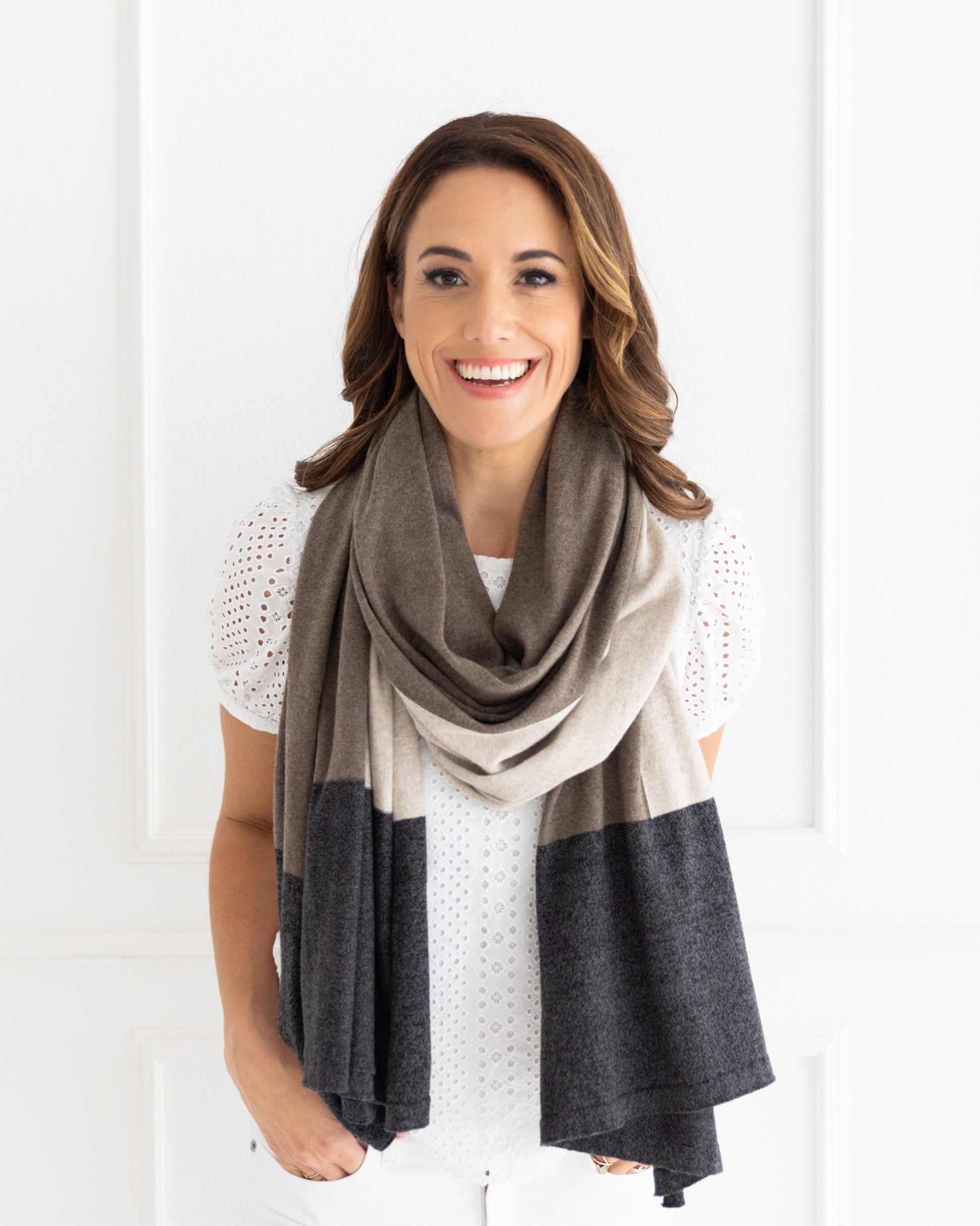 Woman wearing the Dreamsoft Travel Scarf in Brownstone Colorblock which is a brown, tan and gray scarf, worn as a modern loop scarf around her neck