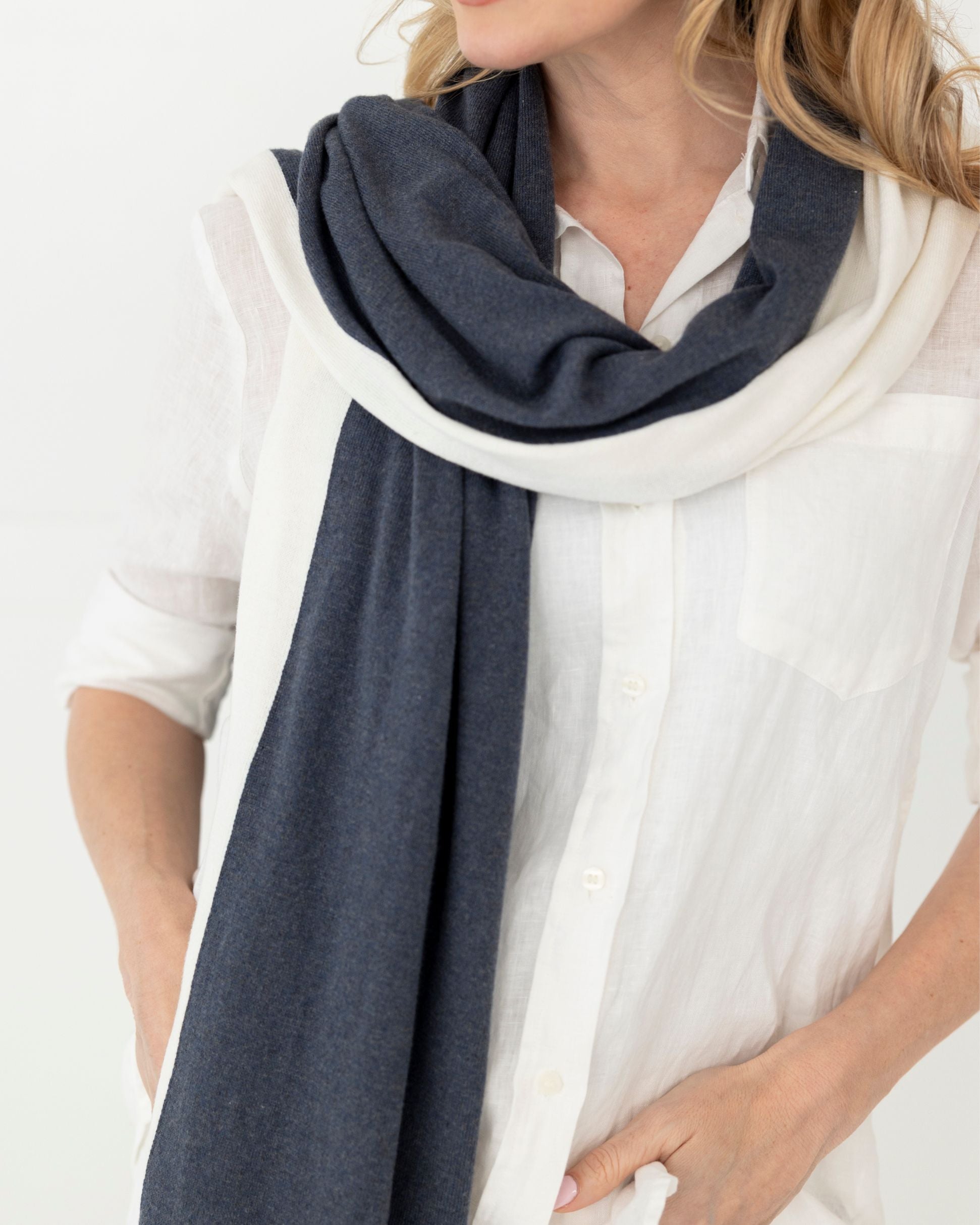 Woman wearing the Dreamsoft Travel Scarf as a scarf in Denim Colorblock which is a dark blue, slate blue and cream scarf