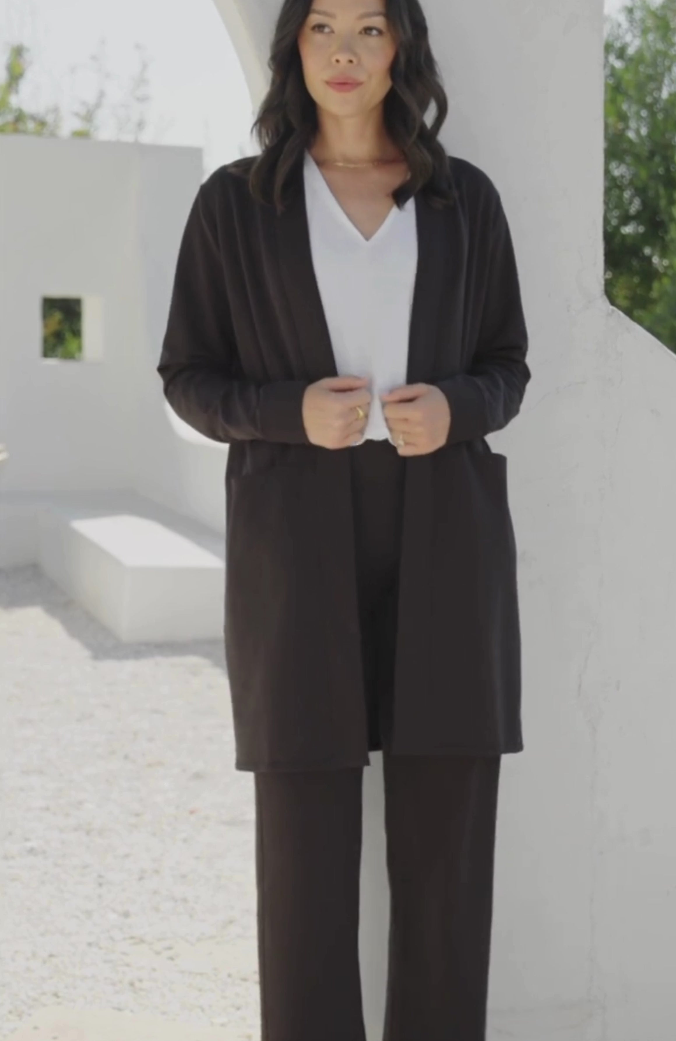 Woman shown wearing black cardigan with hands in her pockets