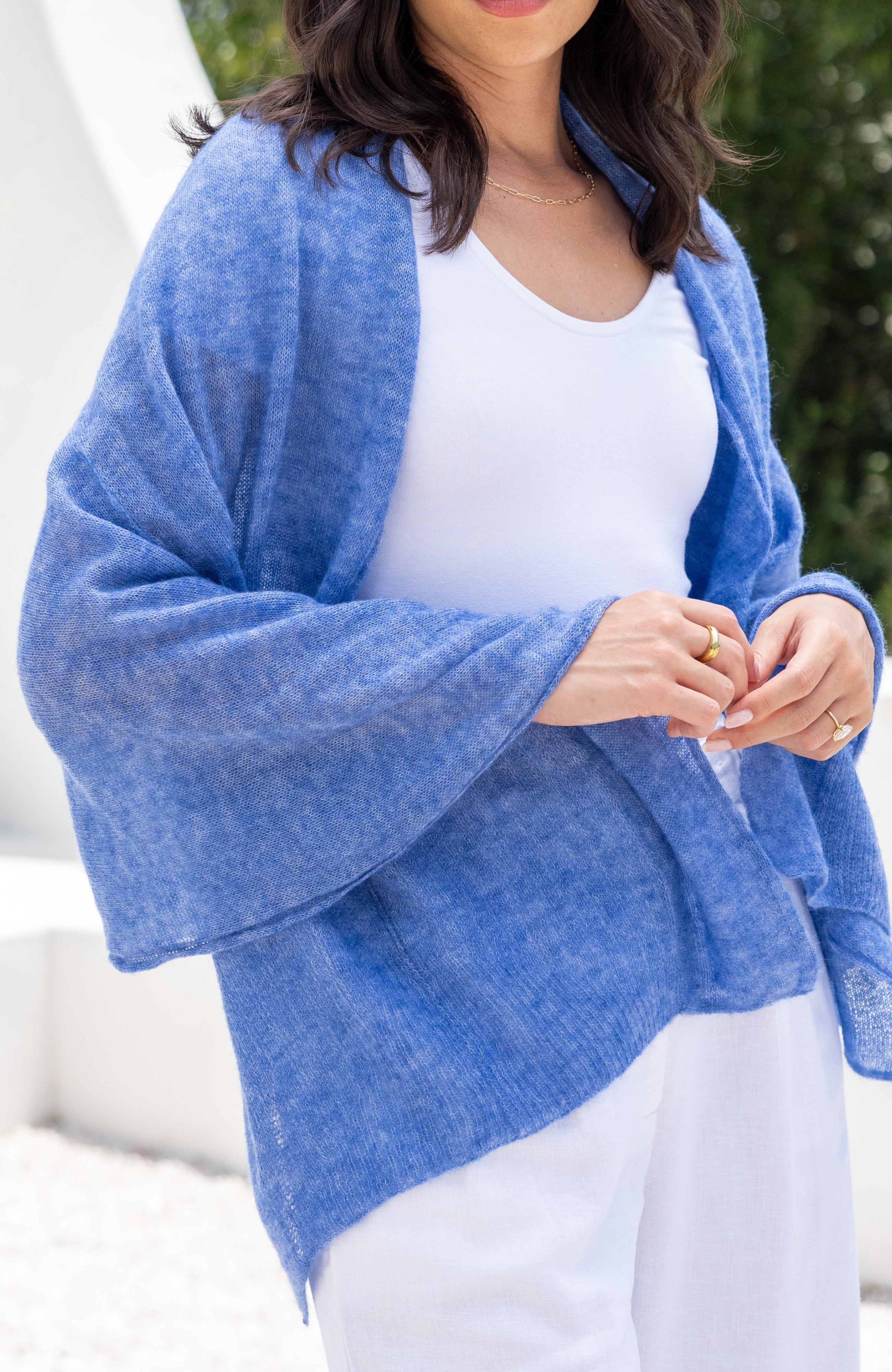 Woman shown wearing a blue scarf draped over her shoulders