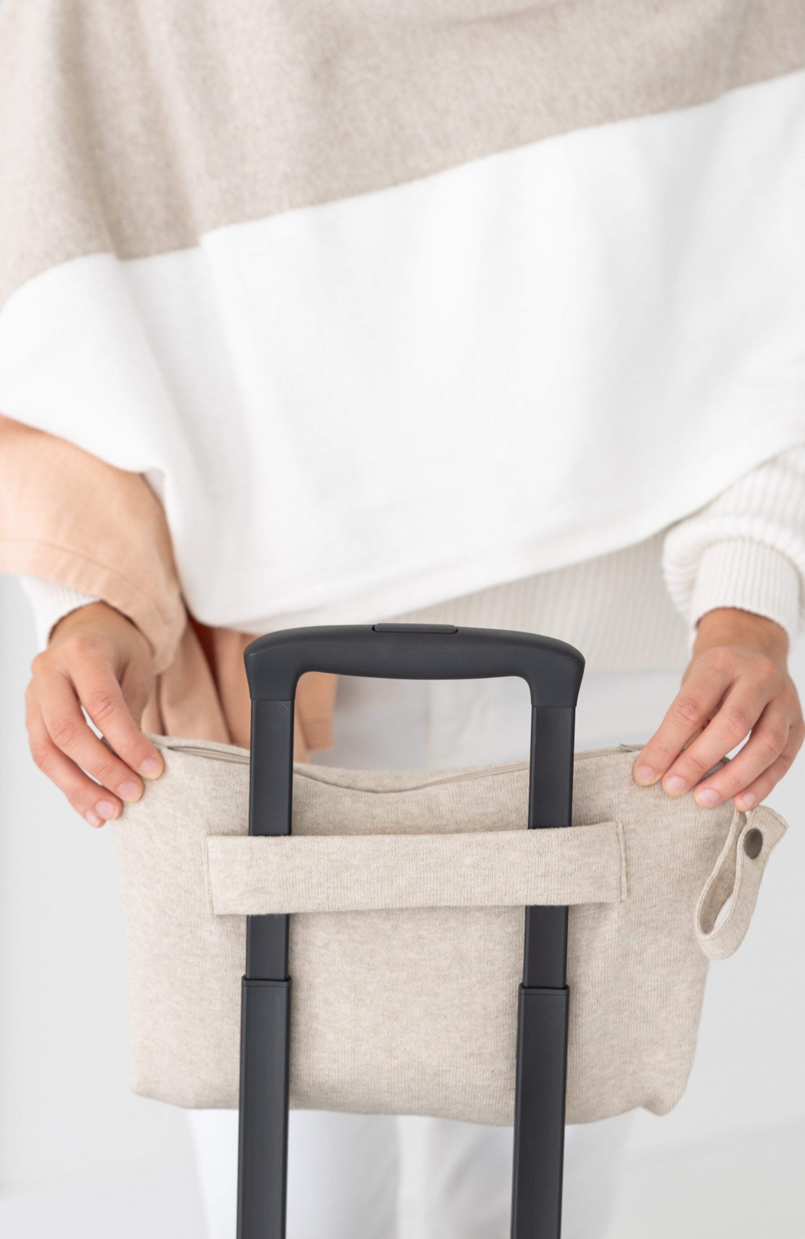 Woman shown putting beige carry pouch on luggage handle