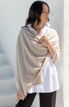 Woman shown wearing a beige scarf draped around her shoulders