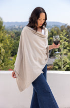 Woman wearing a Beige Scarf draped around her shoulders and holding glass of wine