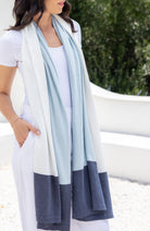 Woman wearing a light blue, white and denim scarf draped around her neck