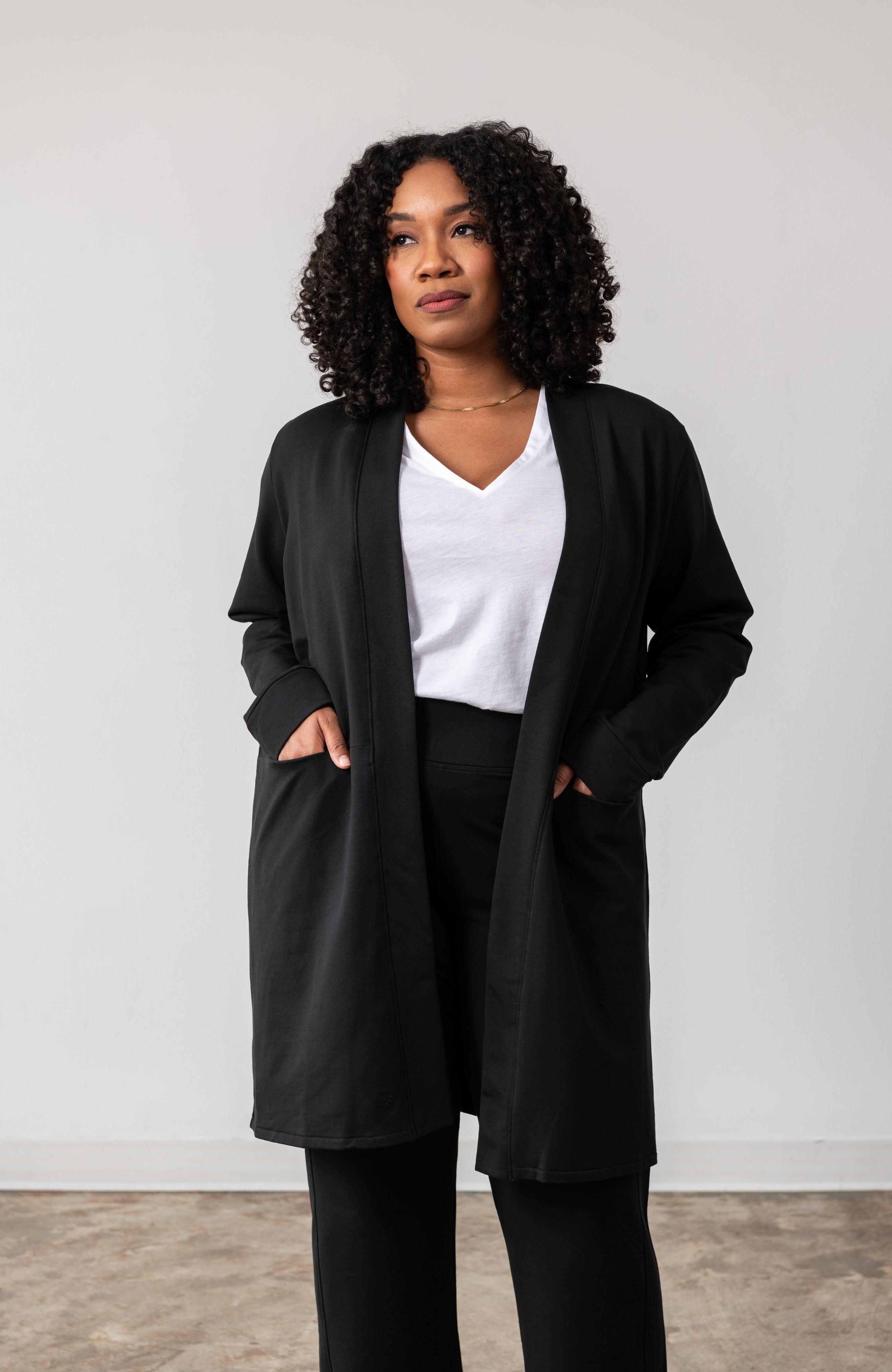 Woman shown wearing black cardigan with hands in her pockets