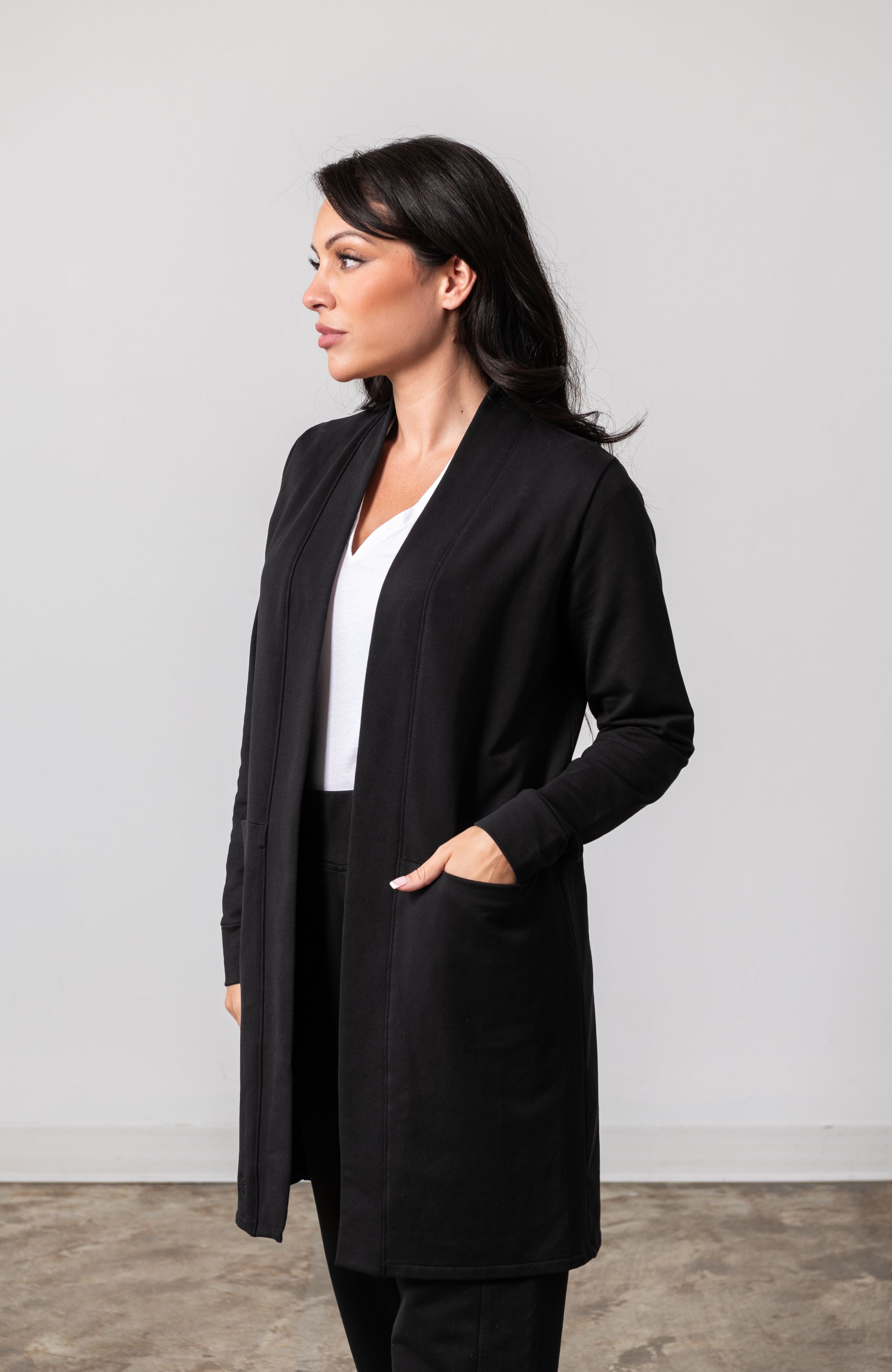 Woman shown wearing black cardigan with her hand in her pocket