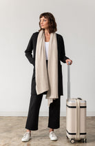 Woman shown wearing black cardigan with beige scarf around her neck