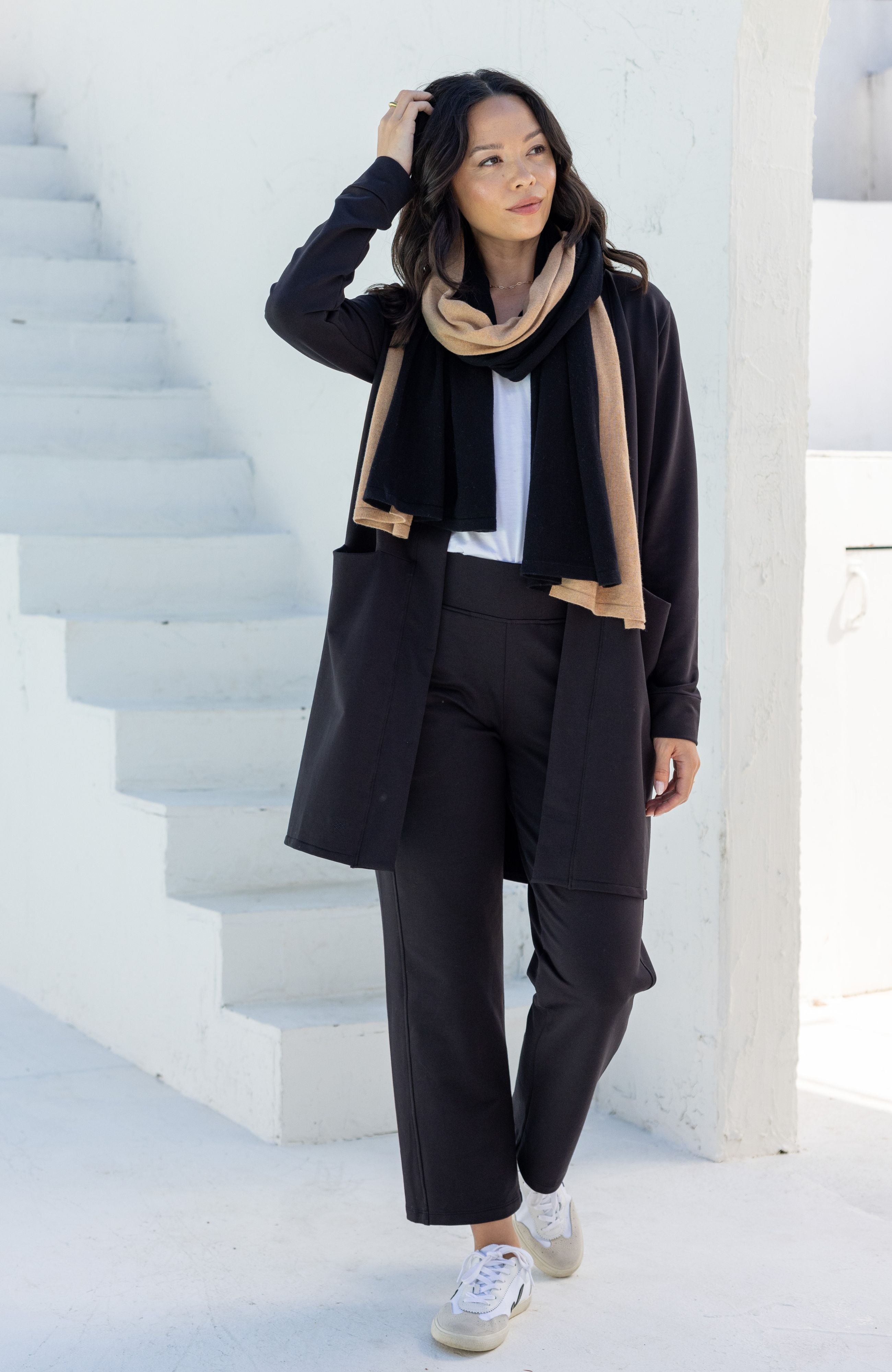 Woman shown wearing black cardigan with beige and black scarf around her neck