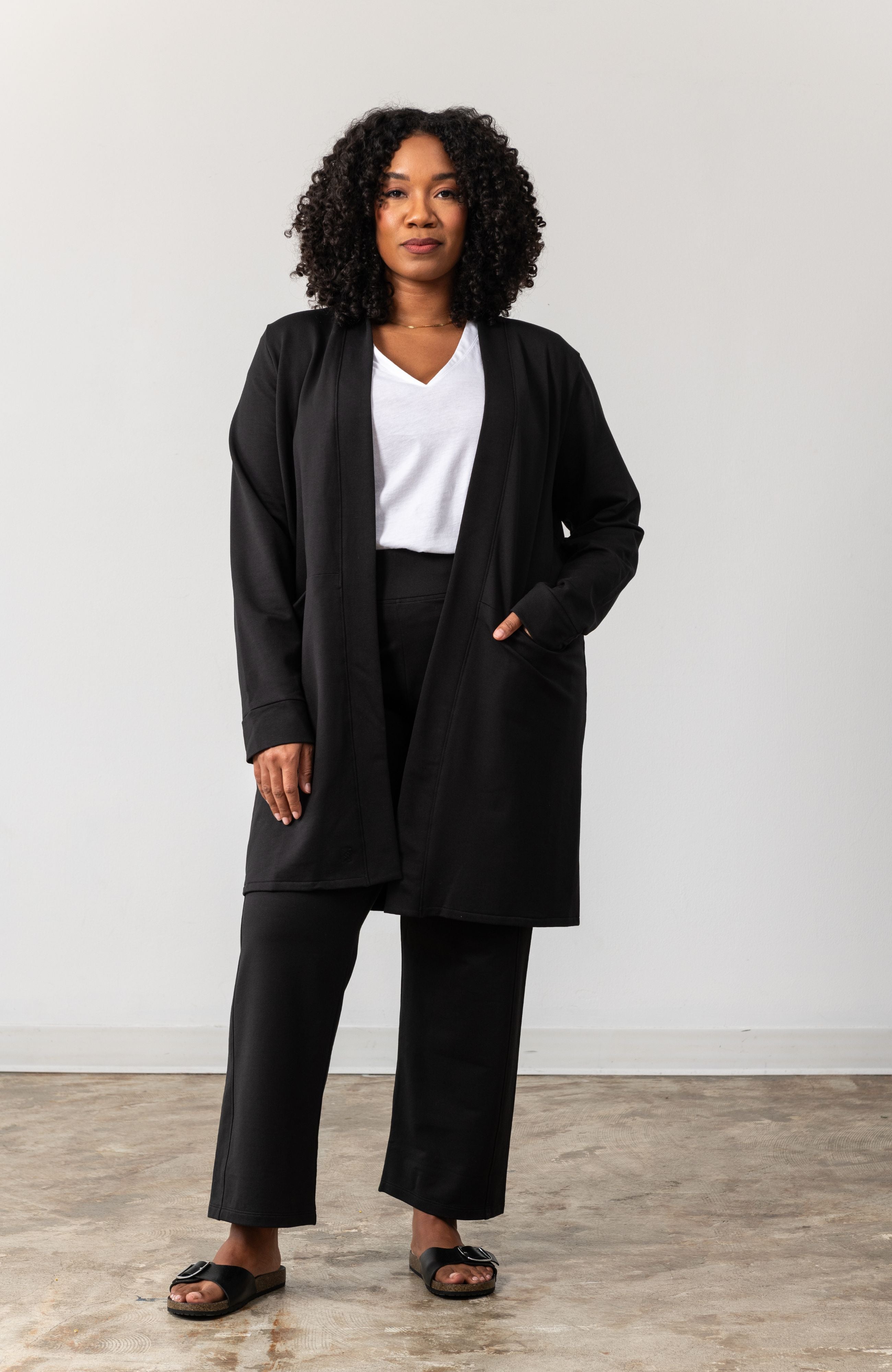 Woman shown wearing black cardigan with  her hand in her pocket