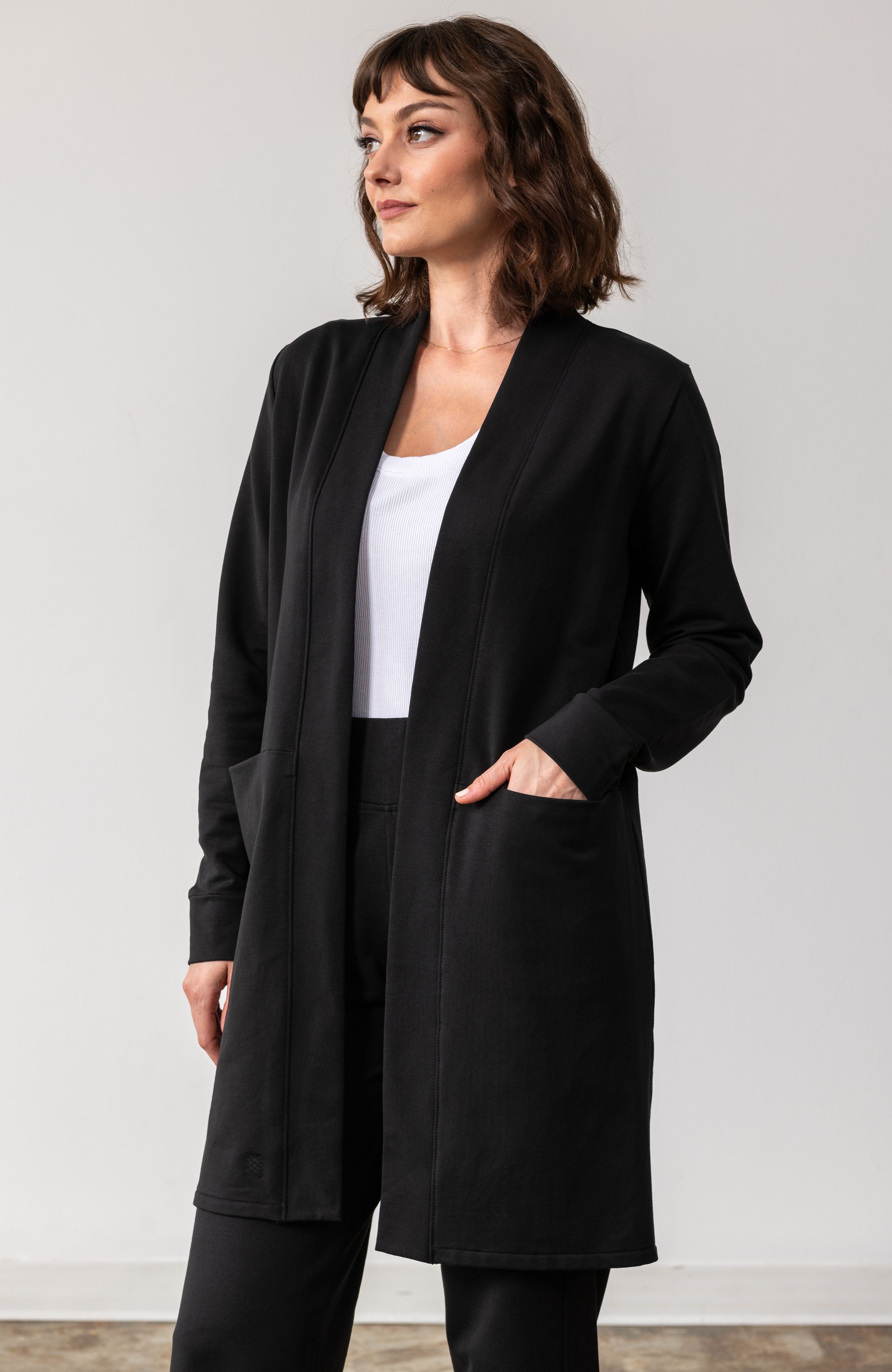 Woman shown wearing black cardigan with her hand in her pocket