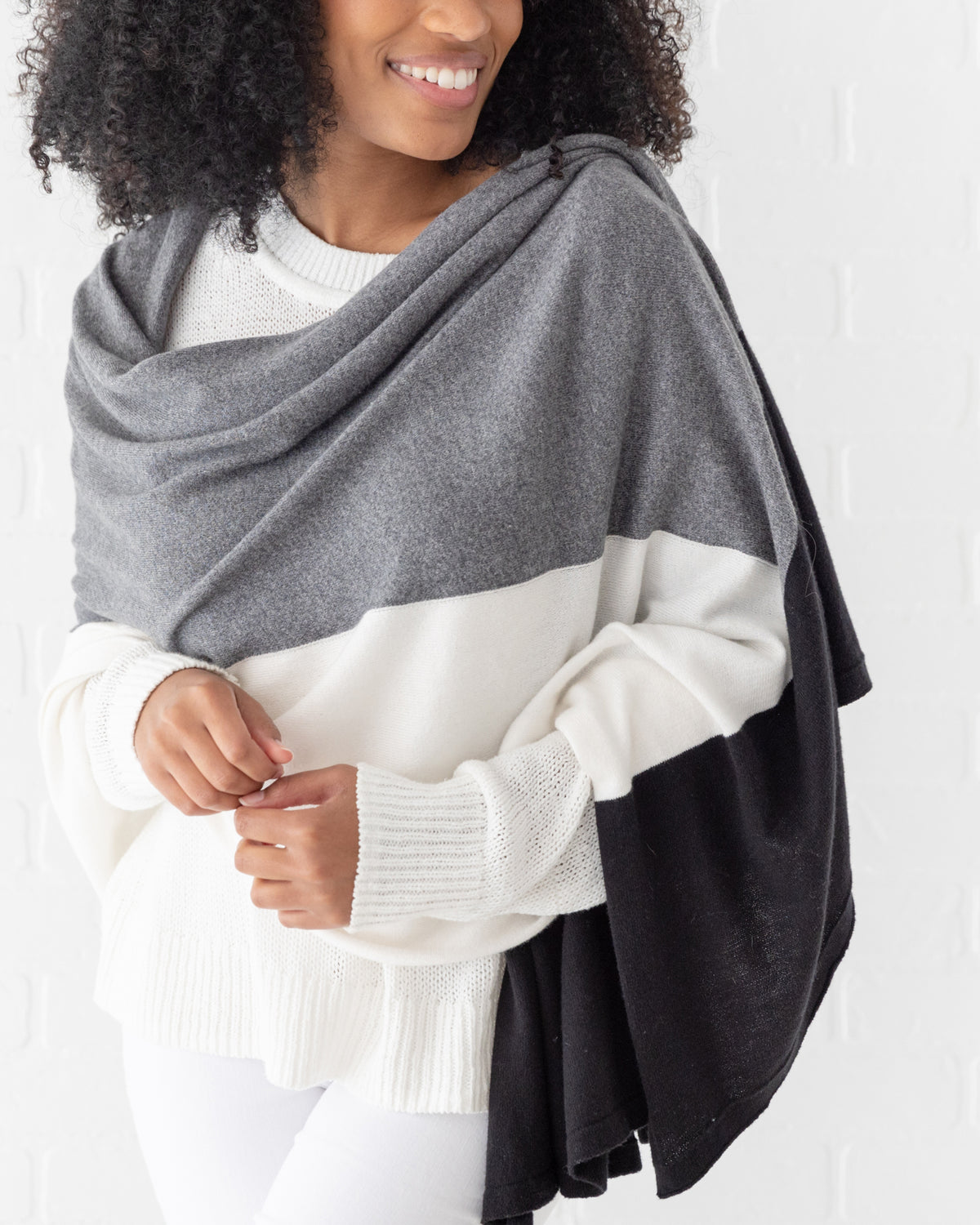 Woman wearing the Dreamsoft Travel Scarf in Gray Colorblock which is a black, gray and cream scarf, in the wrap style