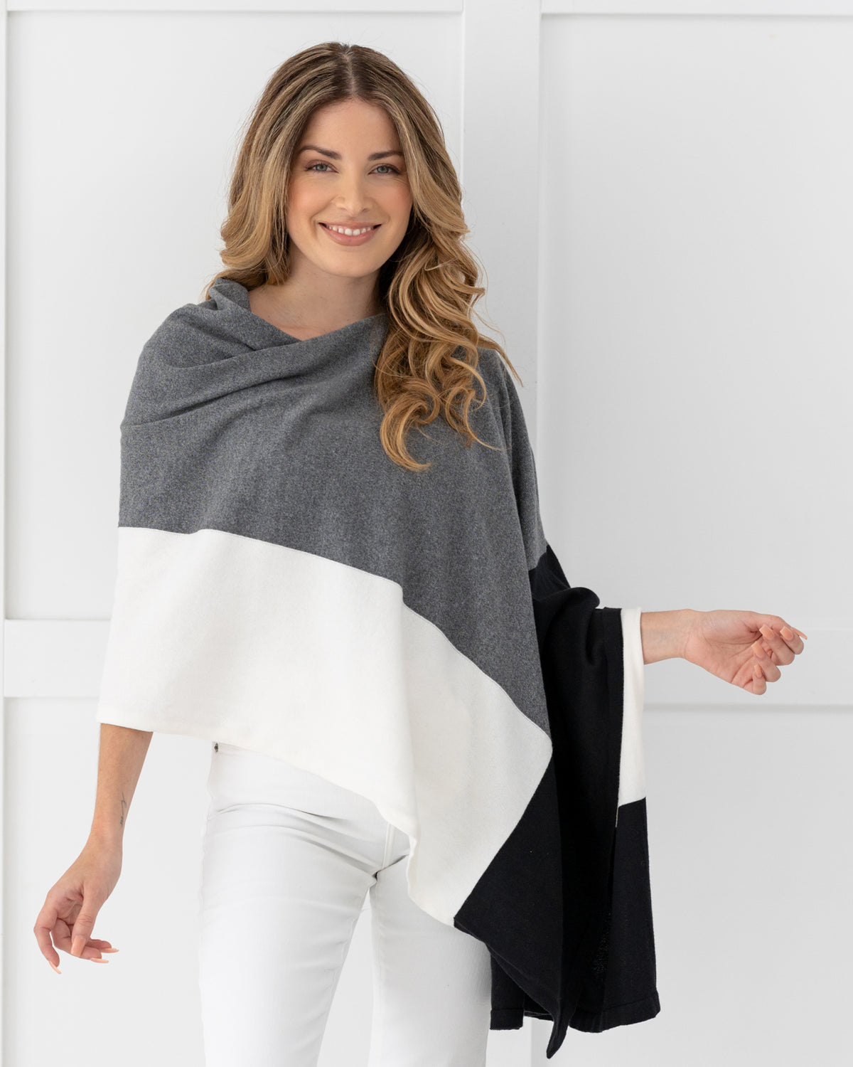 Woman wearing the Dreamsoft Travel Scarf in Gray Colorblock which is a black, gray and cream scarf, while smiling and looking at the camera