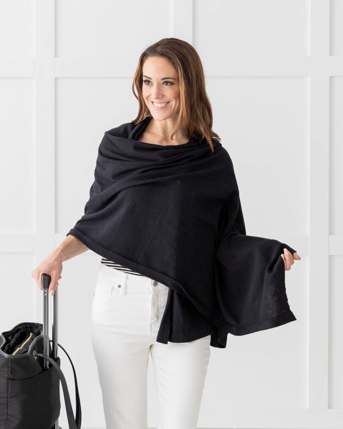 Woman wearing the Dreamsoft Travel Scarf in Black, pulling a suitcase