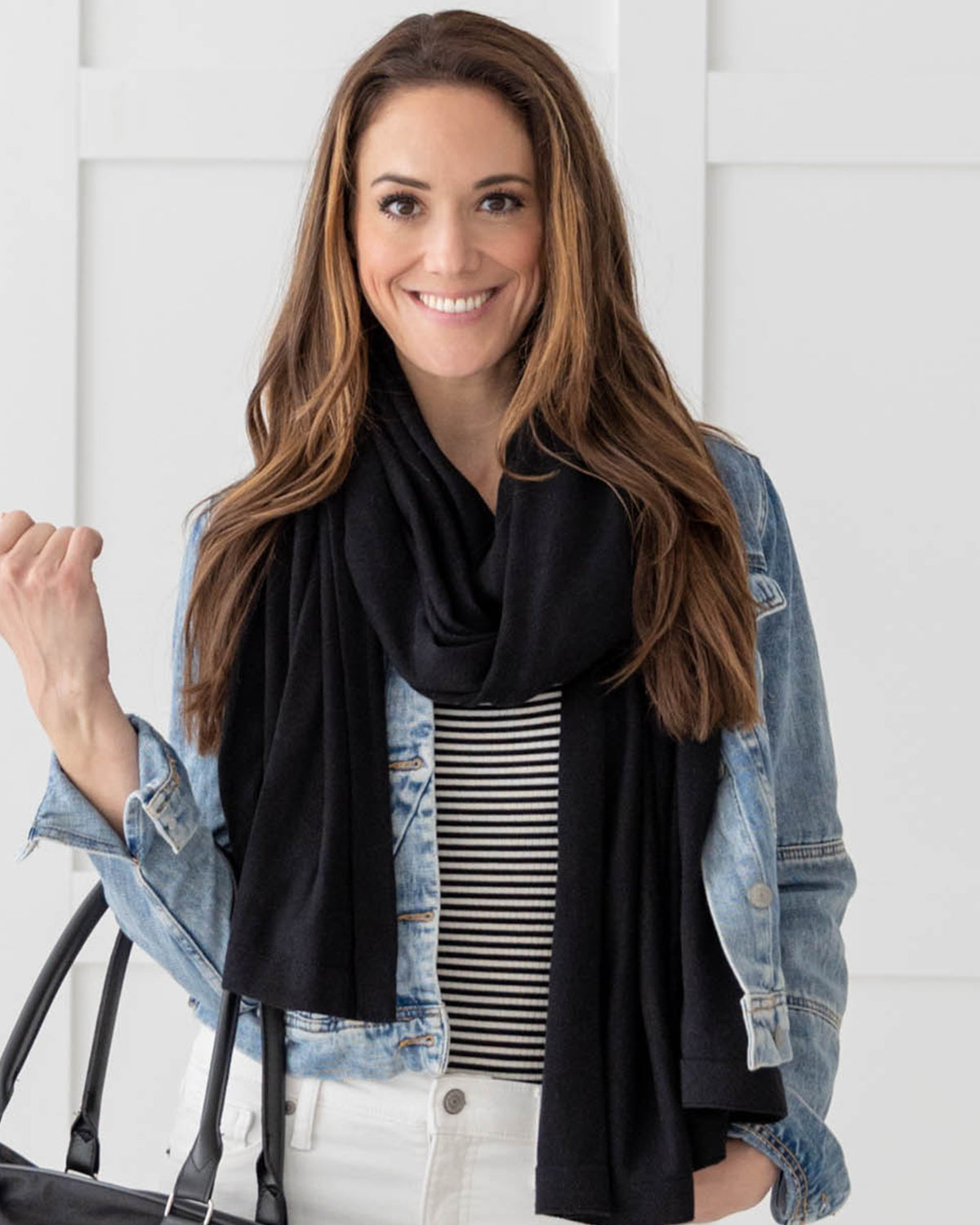 Woman wearing the Dreamsoft Travel Scarf in Black, holding a bag and smiling